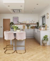 Kitchen with grey cabinets, wooden flooring and pink bar stools.