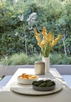 Fruit and vase of flowers on kitchen island with view to garden
