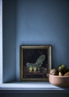 Framed still life painting and bowl of fruit on blue painted shelf