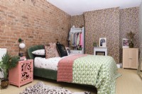 Modern bedroom in pinks and greens with a leopard print wallpapered feature wall and chimney breast and a wall with exposed brickwork 