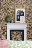 A white and black fire surround and mantelpiece against a leopard print wallpapered wall