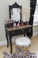 White furry covered stool and an upcycled decorative dressing table painted in black with a vinyl leopard print covered top