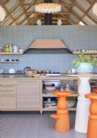 Bright orange barstools in contemporary kitchen with tiled feature wall
