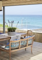 Outdoor dining table and chairs on decked terrace with sea views