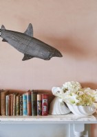 Detail of shark sculpture above books on mantelpiece