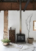 Wood burning stove and log store next to exposed brick wall