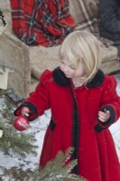Little girls wearing red vintage coat and decorating outdoor Christmas tree in the snow