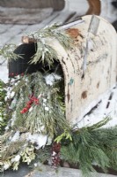 Old mailbox decorated for Christmas with natural greenery and berries.