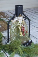Christmas outdoor lantern decorated with greens and berries attached with burlap ribbon