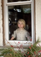 Little girl wearing a vintage dress watching for Santa from a window