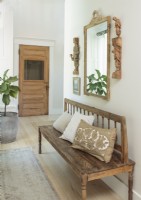 A vintage bench and mirror offer a comfy spot in the hallway.