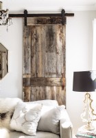 A sliding barn door constructed from salvaged wood adds a textural rustic  note to the living room.