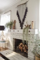  Washed in white, the fireplace is well equipped for chilly nights. .â€ Barely-there window treatments allow intricate pieces, like the tasseled wall hanging to take center stage.