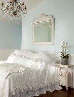 Nikki's penchant for antiques carries into the master bedroom where a vintage mirror was constructed from a salvage frame. The piece rustic finish is balanced by feminine bed linens and a romantic chandelier with aqua pendants.