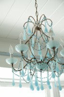In keeping with the home's main color accent, an aqua chandelier takes center stage above the dining room table.