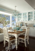 Overlooking the Intercoastal waterways the eating area off the kitchen is the family's favorite spot to share their daily meals. Nikki had the cabinets built-in, and she painted the back a soft sky blue to recall the near-by waters and allow her white dishes to stand out.