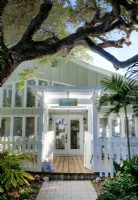 The cottage welcomes with a traditional picket fence and tropical setting. The exterior soft colors hint at the interior's subdued palette.