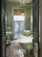 Shutters lead to the bath, where a clawfoot tub and a Turkish marble sink on old stone pavers set an old-world mood.