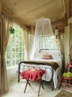 High ceilings and plenty of natural light make the small space appear like an extension of the woods outside. The the tree house was designed around this iron bed, which was originally in a guest room in the main house. 
