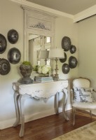 Antique serving domes make an intriguing radial arrangement. They hang on either side of the mirror in a balanced but asymmetrical design statement, in keeping with the coupleâ€™s relaxed style. 