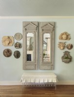 In the hallway, a pair of antique mirrors is flanked with shapely and well scaled stone items displayed with an eye toward balance. 