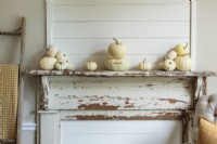 A vintage fireplace surround gets a subtle Fall makeover with grouping of tiny gourds in the same color family.