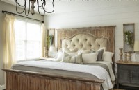  A shiplap wall and a variety of aged woods create a sense of history in the coupleâ€™s bedroom. The king-sized showstopper bed features a distressed headboard frame with tufted upholstery layered with a rustic whitewashed wooden mantel panel. 