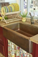 In true farmhouse fashion a sink skirt covers the plumbing below an aged copper basin.
