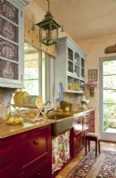 Soft blues, country red and ochre yellows are the basis for the kitchenâ€™s dÃ©cor. The upper cupboards match the roomâ€™s trim while the lower cabinetry sports a rich crimson hue.