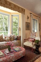 An inviting window seat and a slipcovered French chair are sited at the heart of the big hall. A parade of chic pillows presents a mini-history of textile artistry.
