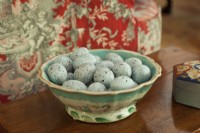 An antique majolica bowl coddles heavenly blue eggs. 
