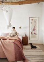 Woman reading in bed with pet dog on floor