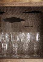 Detail of wine glasses on shelf backed with hessian sack