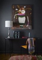 Colourful painting on black painted wall in modern bedroom
