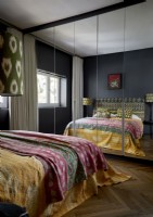 Colourful bedspread in bedroom with black painted walls