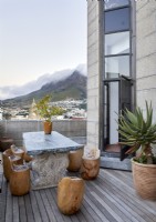 Marble table and wooden log seats on balcony with mountain views