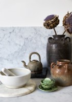 Cut artichoke flowers in ceramic pot on kitchen worktop