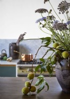 Flower and fruit display in large ceramic pot in country kitchen 