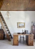 Wooden desk in country study with ladder style staircase to side