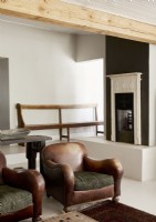 Fireplace on platform in modern living room with leather armchairs