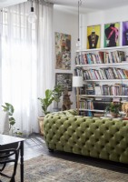 Green studded sofa in living room with large bookshelves and artwork