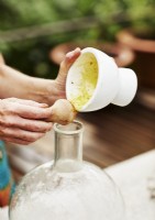 Woman pouring contents of bowl into glass jar