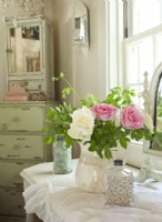 Collected shells and sea glass gather around fresh flowers to create a lovely still life. A vintage medicine cabinet and a dresser are home to everyday necessities.  