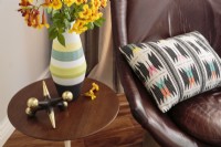 A  leather armchair is accentuated with a colorful pillow with a geometric pattern.
