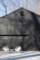 Black barn style garage with outdoor seating.