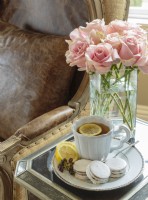 Tea, cookies and roses set on a mirror table are perfectly at home next to a cozy leather chair.