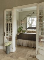  In the master bedroom, travertine floors are an eco-friendly choice that offer subtle pattern and easy care. Mirrors take the place of glass in salvaged French doors.