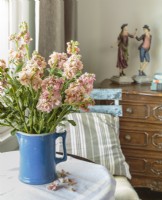A garden chair and pitcher of flowers bring outdoor flavor to the bedroom. 