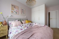 Bedroom with a large dressed bed in pastel colors