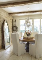 Leah Anderson decorates with fewer pieces, each with show-stopping style, like the pedestal table and a salvaged, gothic-arch window made into a stately mirror frame.